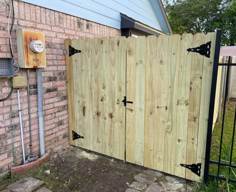 New wood double gate by a brick wall