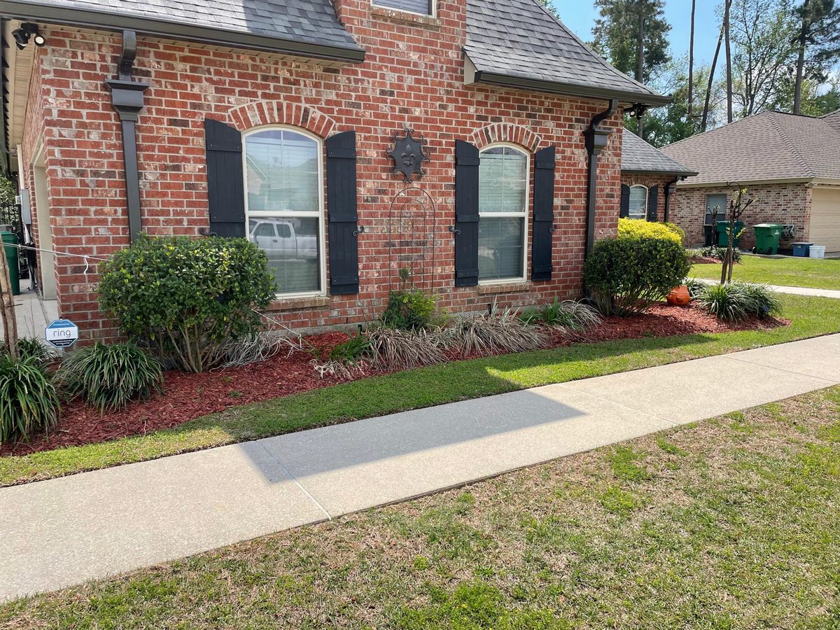 Landscaping with fresh mulch beds and shrubs along a brick home