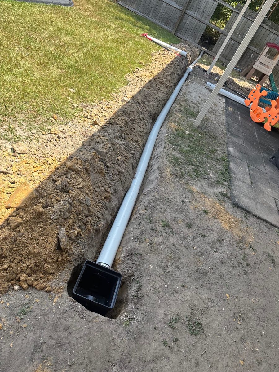 French drain pipe set in a backyard trench